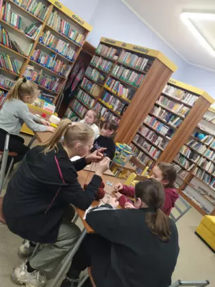 Uczestniczki zajęć siedzą przy stole i szydełkują.