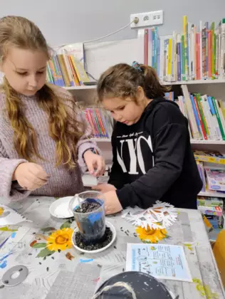 Dziewczynki sypią słonecznik do karmnika.