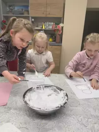 Dziewczynki pianką wyklejają bałwanka.