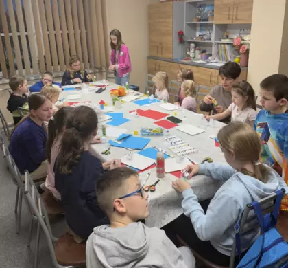 Dzieci na zajęciach wycinają z kolorowego papieru postacie Muminków.