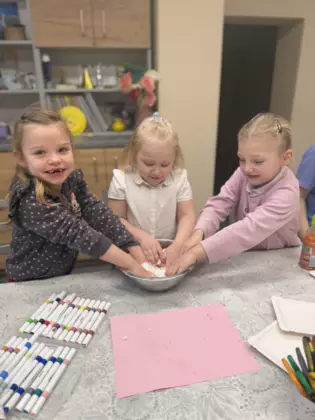 Dzieci w dużej misce mieszają mąkę i piankę do golenia tworząc sztuczny śnieg.