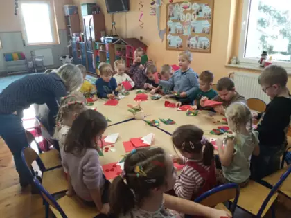 Przedszkolaki przy wspólnym stoliku wykonują prace dla babci i dziadka.