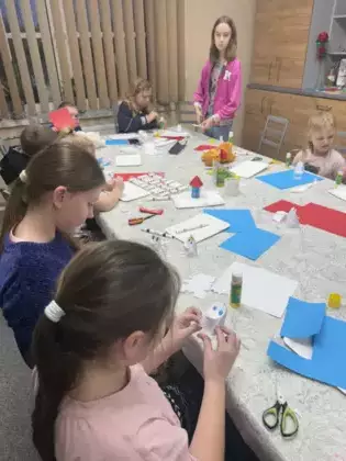 Dzieci na zajęciach wycinają z kolorowego papieru postacie Muminków.