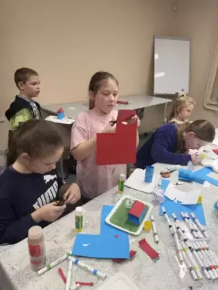 Dzieci na zajęciach wycinają z kolorowego papieru postacie Muminków