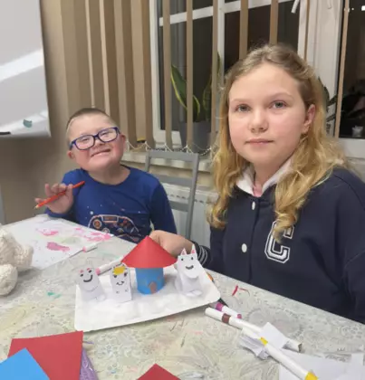 Dziewczynka i chłopczyk. Na stole przed nimi stoi makieta Muminków.