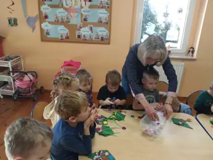 Pani bibliotekarka pomaga wykonać laurkę przedszkolakom.