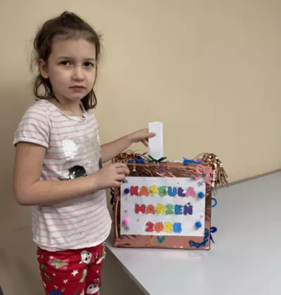 Dziewczynka wrzuca swoje postanowienia noworoczne do kapsuły marzeń.