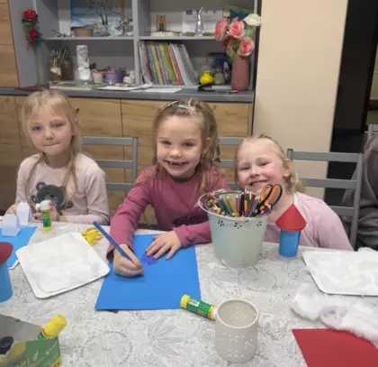 Trzy małe dziewczynki kolorują obrazki.