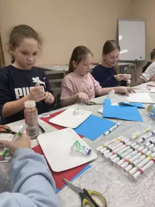 Dzieci na zajęciach wycinają z kolorowego papieru postacie Muminków.