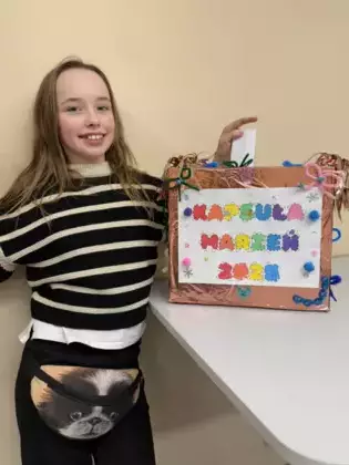 Dziewczynka wrzuca swoje postanowienia noworoczne do kapsuły marzeń.