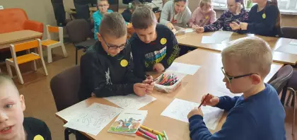 Dzieci kolorują obrazek kredkami.