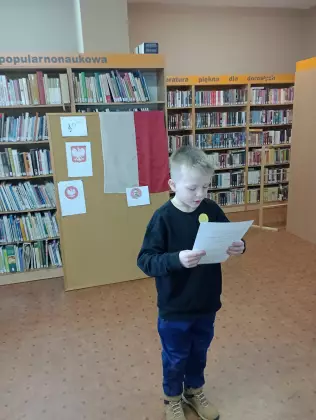 Chłopiec czyta w bibliotece.