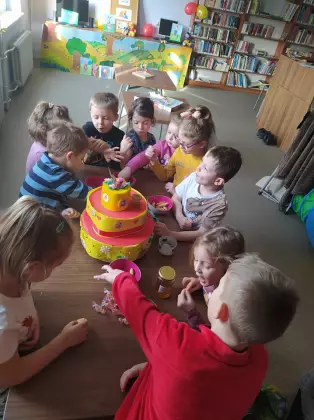 Dzieci wokół tortu, częstujące się miodem.