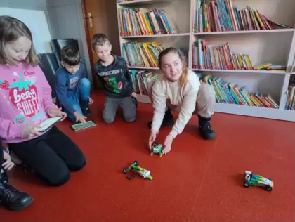 Dzieci próbują jazdę złożonymi samochodzikami z Lego.