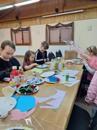 Uczestnicy warsztatów malują farbkami zimowy pejzaż.