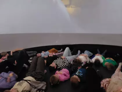 Uczestnicy leżą na podłodze w kopule kina sensorycznego i oglądają seans filmowy.