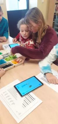 Uczestnicy zajęć budują autka z klocków Lego.