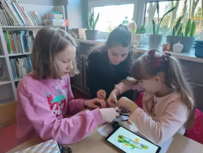 Dziewczyny składają autko z klocków Lego.