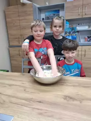 Chłopcy na warsztatach kulinarnych wyrabiają ciasto na faworki.