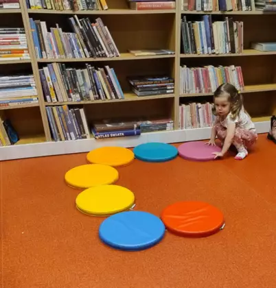 Mała dziewczynka układa okrągłe płaskie poduszeczki.