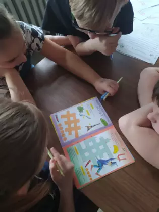 Dzieci rozwiązują krzyżówę ortograficzną.