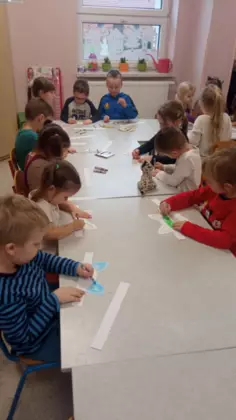 Przedszkolaki malują kocie uszka z papieru.