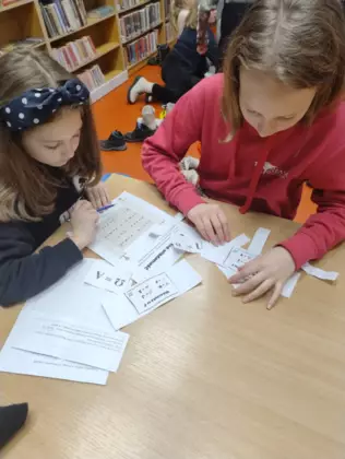 Uczestniczki zajęć rozwiązują szyfr, aby przejść do kolejnej zagadki.