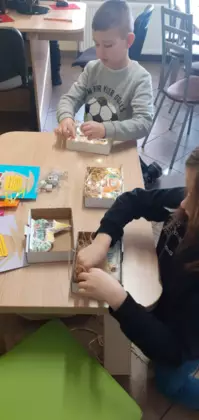 Dzieci przyklejają lampki do pracy plastycznej.