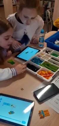 Dziewczyny układają klocki Lego.