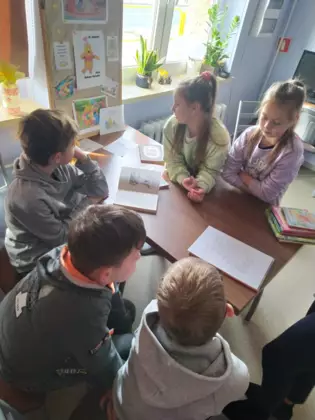 Trzech chłopców i dwie dziewczynki czytają książkę o Kubusiu Puchatku.