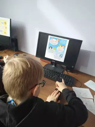 Chłopak korzysta z komputera w bibliotece.