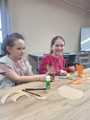 Dziewczyny wykonują kota w butach z rolek papierowych.