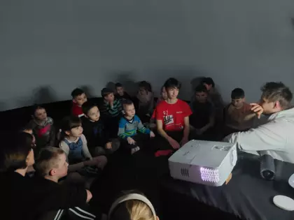 Uczestnicy siedzą na podłodze w kopule kina sensorycznego i oglądają seans filmowy