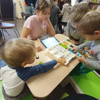 Uczestnicy zajęć budują autka z klocków Lego.