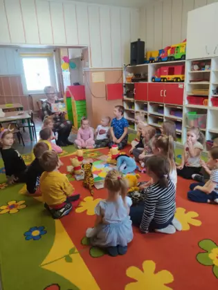 Przedszkolaki słuchają bajki czytanej przez panią bibliotekarkę.