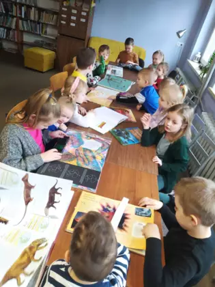 Przedszkolaki oglądają książeczki o dinozaurach.