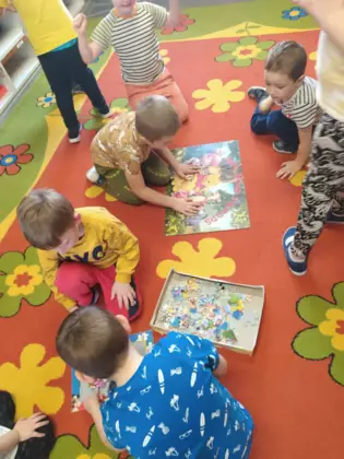 Przedszkolaki na dywanie oglądają książeczki.