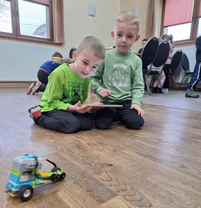 Chłopcy jeżdżą samochodzikiem złożonym z klocków Lego.