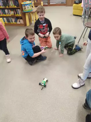 Chłopcy jeżdżą autkiem sklejonym z klocków Lego.