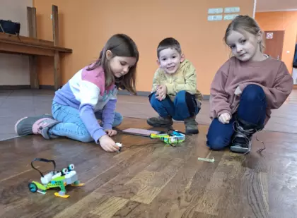 Uczestnicy zajęć składają żabkę z klocków Lego.