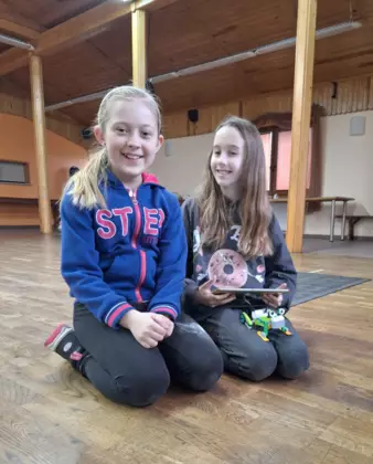 Dziewczyny pokazują jeżdżące autko złożone z klocków Lego.