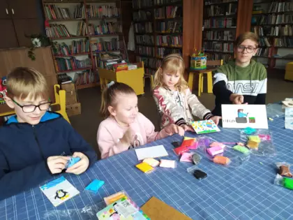 Uczestnicy zajęć wyklejają plasteliną obrazki.