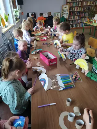 Przedszkolaki wykonują pracę plastyczną - dinozaura z papieru.