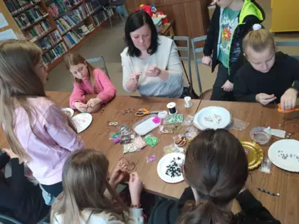 Uczestnicy warsztatów nawlekają koraliki na sznurek.