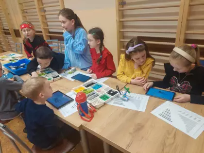 Uczestnicy warsztatów składają autka z klocków Lego.