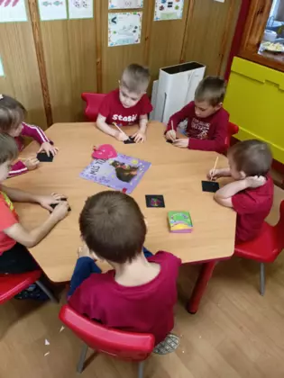 Przedszkolaki na karteczka malują serduszka walentynkowe.