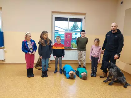 Trener wraz z psem pokazują dzieciom pozycję bezpieczną.