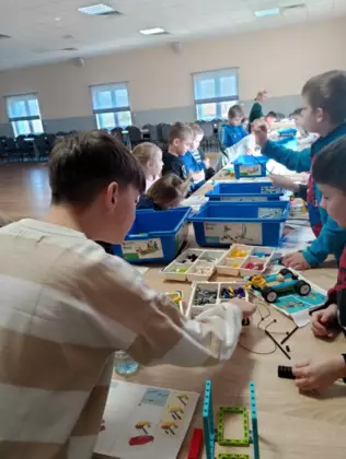Uczestnicy zajęć w trakcie tworzenia swoich pojazdów i budowli z klocków lego.