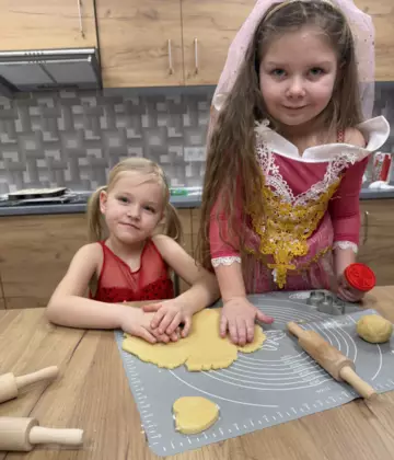 Dziewczynki wykrawają kształty z ciasta.
