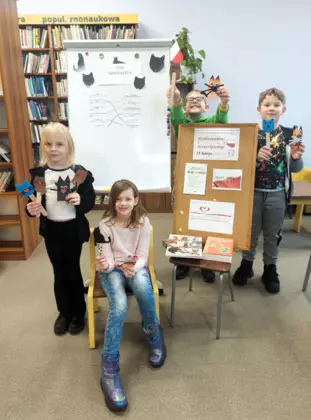 Grupowe zdjęcie dzieci z zajęć literacko-plastycznych. Uczestnicy zajęć prezentują prace plastyczne.